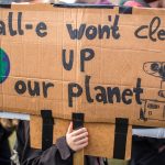 Protester holding a sign saying Wall-e won't clean up our planet. Rally against climate change and environmental pollution