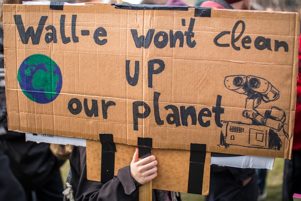 Protester holding a sign saying Wall-e won't clean up our planet. Rally against climate change and environmental pollution